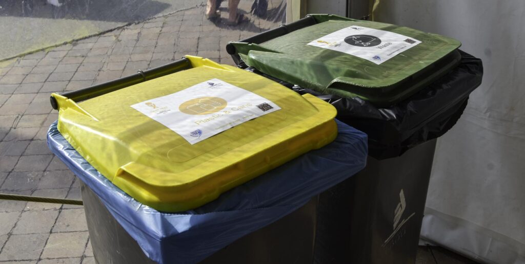 11. Ensure Proper Waste Bin Placement and Signage<br>Four waste management points were distributed between the race office and the race village tent with waste, paper and plastic bins. The days where bottled beer was offered, they were asked to return the bottles at the bar (inside the race village tent) to be proper recycled. It was not possible to include a compostable waste bin as this service is not available in L