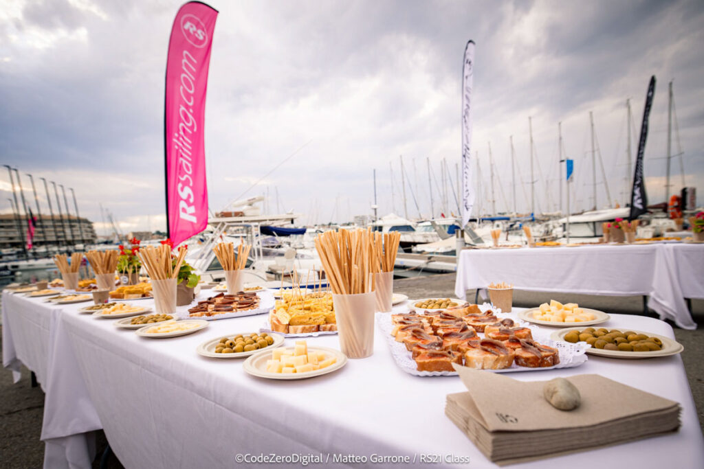 17. Offer Vegetarian or Vegan Alternatives<br>During the RS21 World Championship racing days (from September 23 to 28) we ensured that vegetarian and vegan alternatives were available to all participants.

Daily Meals: From September 23 to 28, meals were served to the sailors after the races. Apart from the special events on the 23rd (inauguration), the 26th (crew dinner), and the 28th (closing ceremony), a pasta dish was provided daily with two options: one vegan and one containing either meat or fish.

Inauguration (September 23): The inauguration event featured a variety of appetizers. Vegan and vegetarian options included olives, cheese, and Spanish omelette.

Crew Dinner (September 26): The crew dinner consisted of a seafood rice dish. The meal began with a comprehensive selection of appetizers, including: potato salad salad bowl, gazpacho (cold tomato soup) shots, guacamole with chips and hummus.