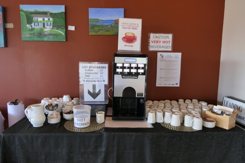 3. Serve Food with Plastic-Free Dinnerware<br>3. Gulf Harbour Yacht Club has always used plastic-free beverage glasses, china, and cutlery for its food and bar services.During the 2025 WOWW event, we reaffirmed the club’s commitment to plastic-free food and bar service with caterers and volunteers. Morning coffee service was supplied with china mugs, metal teaspoons, and china cream pitchers. (Photo 3a) China plates and bowls, and cloth tablecloths, were used for all food service. (Photo 3b) Lunches on participating boats were  provided in bags made of hessian with paper labels and cotton strings. Sandwiches were wrapped in wax paper and fresh fruit required no wrapping. Prizegiving Night tables were set with linen tablecloths, real glasses, metal cutlery and small paper napkins which were composted after use. Centerpieces were reused. (Photo 3c) Ends of roll paper from printing were repurposed on top of buffet tablecloths to reduce the number of times they needed to be laundered. (Photo 3d)