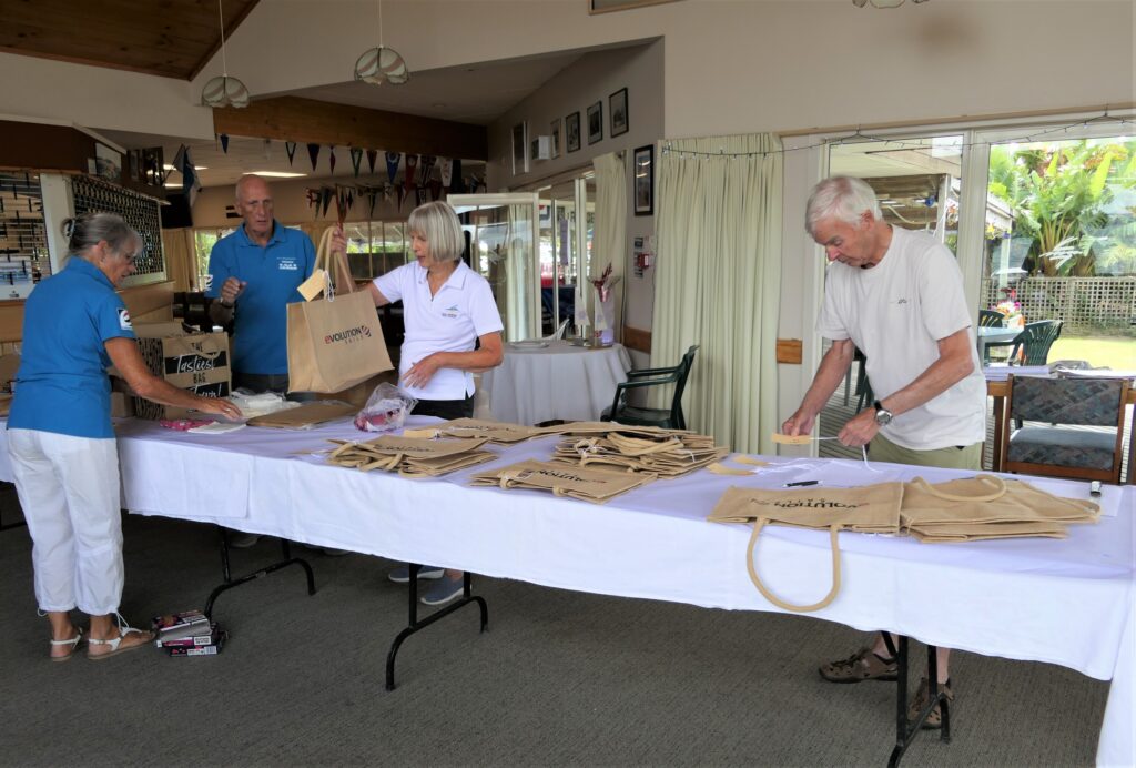 4. Skip Bags or Go Reusable<br>4. On the water sailing events require many supplies and pieces of equipment to be tranferred to yachts by boat owners, yacht club organisers, race crew, and skippers. Without reusable totes or recycled bags, waste could easily get out of hand. The WOWW Green Team made sure that reusable bags and totes were available for the multiple trips to boats, vehicles and the club. (Photo 4a) Packed lunches on boats were provided in bags made of hessian with paper labels and cotton strings. Sandwiches were wrapped in wax paper and fresh fruit required no wrapping. Crews were asked to return all waste/rubbish in the bags, to be disposed of appropriately back at the clubhouse. A bonus came with the use of bags marked with the brandname of Evolution Sails, the 2025 Gold Sponsor. (Photo 4b)
