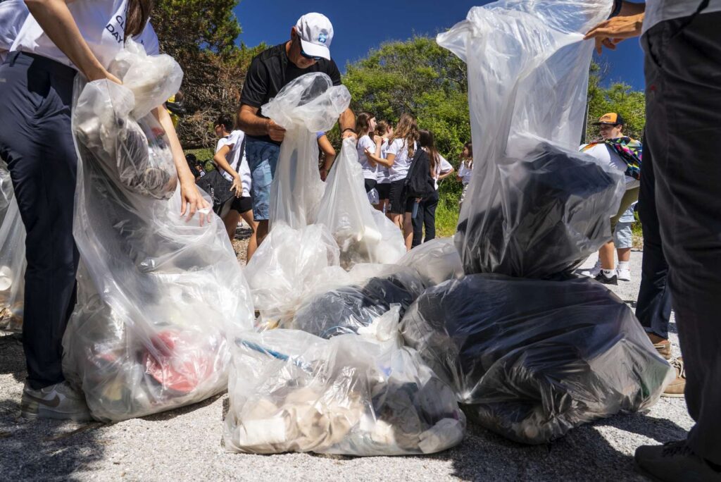 14. Host a Beach or Marina Cleanup<br>A Clean Beach Day was organised the day after the final prize-giving, on June 8th the World Ocean Day, as part of the YCCS sustainability initiatives. Around 100 participants, including some 80 students from the lower secondary schools of Arzachena attended and the event had the patronage of the Municipality of Arzachena – as part of its AgendaBlu 2026 calendar – and carried out in collaboration with the National Research Centre (CNR) of Oristano and the One Ocean Foundation. Approximately 150 kg of waste were collected. The activity involved the students through an educational session led by the CNR of Oristano, including a short explaination of an educational comic magazine "Carrie" on marine pollution. Drawings made by the participating children were collected, helping to raise awareness among younger generations about the importance of protecting the marine environment.
